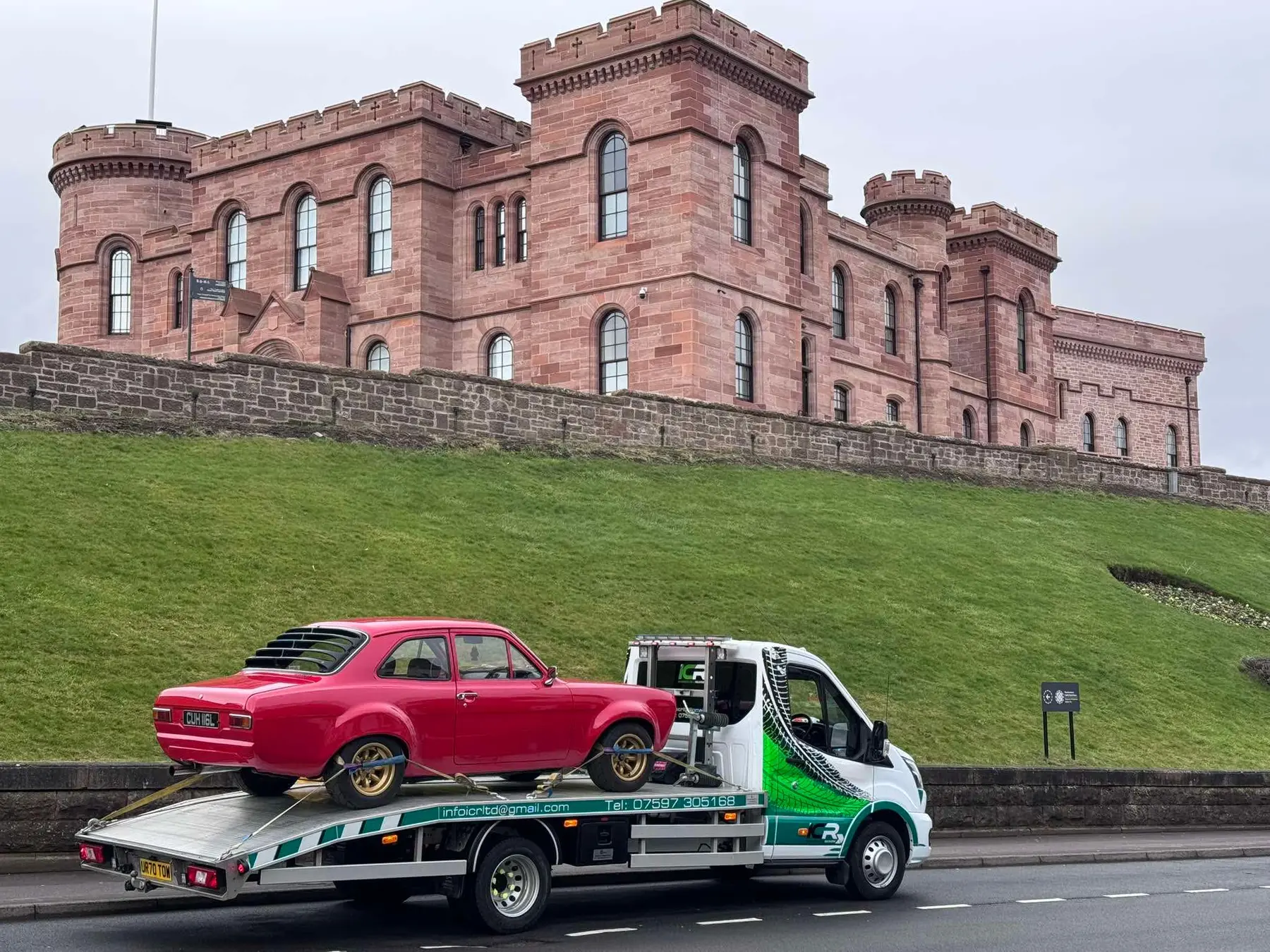 Red classic car being transported by ICR in front of Inverness Castle